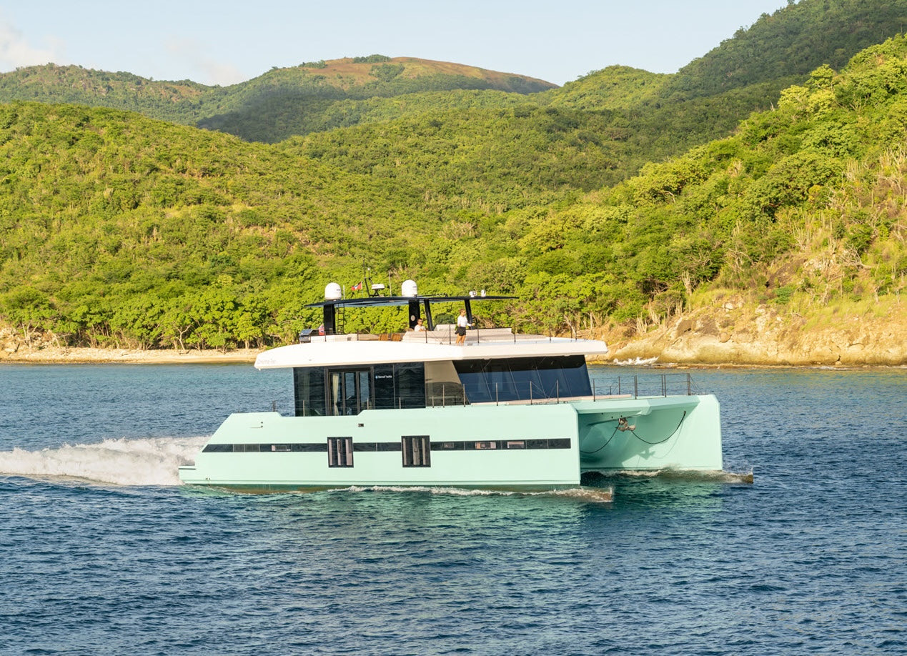 Power catamaran anchored off green Bahamian hills